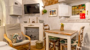 Una habitación acogedora con chimenea, un televisor montado en la pared y una mesa con sillas.