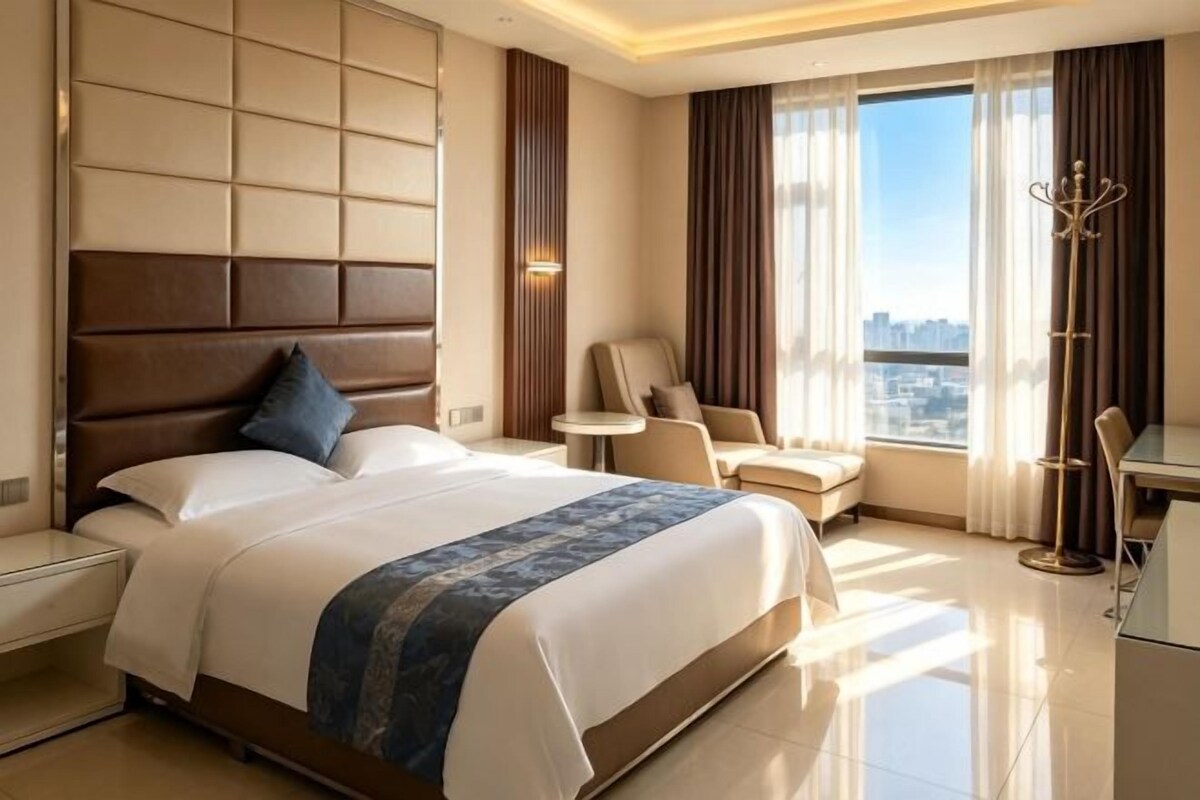 A hotel room with a large bed, a seating area, and a city view.