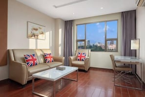 En moderne stue med en sofa, et glasbord, et spisebord med stole og et stort vindue med udsigt over byen.