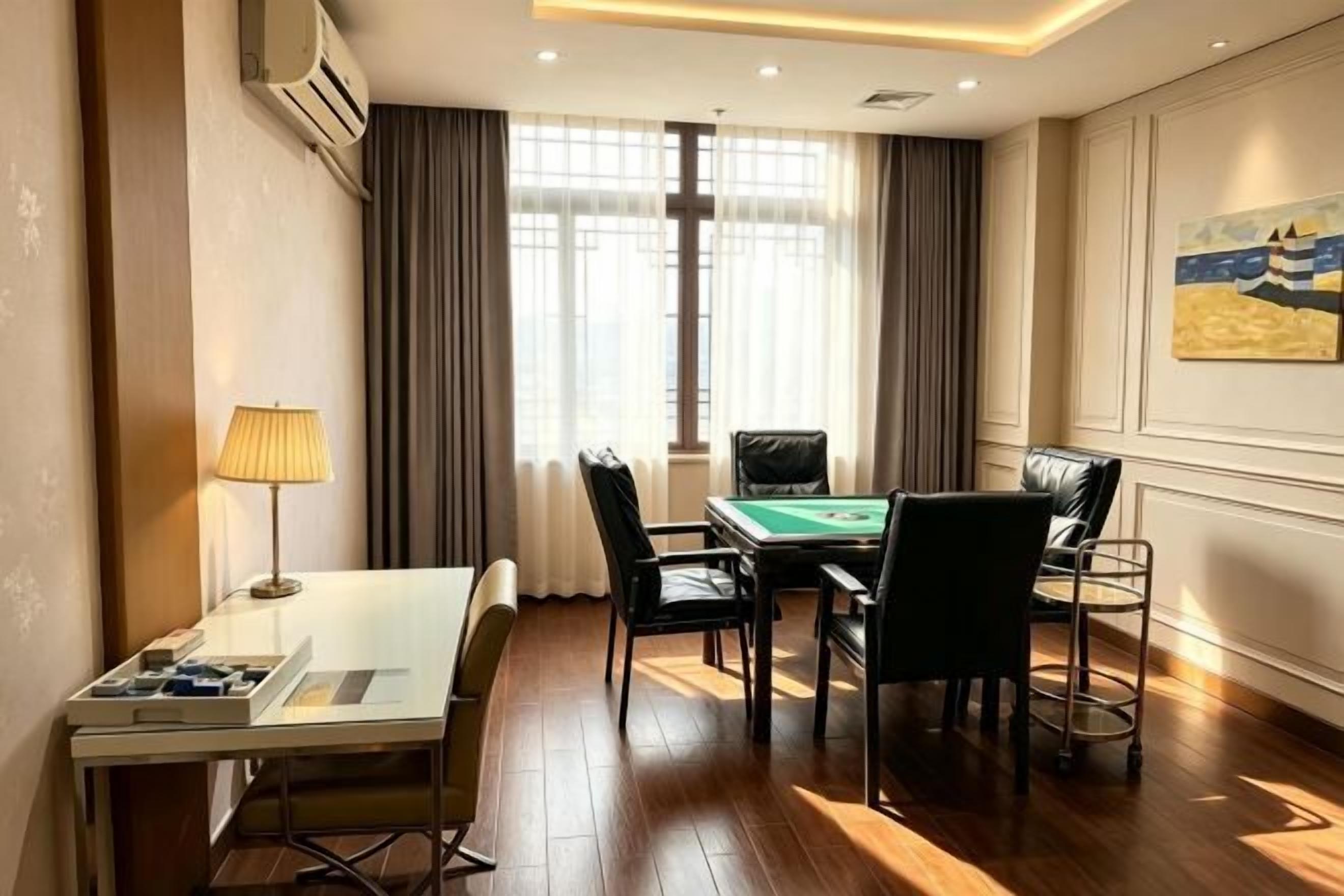 A hotel room with a pool table, a desk with a lamp, and a view of the outdoors through large windows.