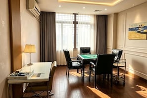 A hotel room with a pool table, a desk with a lamp, and a view of the outdoors through large windows. - Qisheng Hotel (Dongguan)