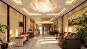 Un hall d’entrée spacieux, agrémenté d’un lustre, d’un coin salon et d’une cuisine en arrière-plan.