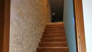 A wooden staircase with a brick wall on one side and a blue wall on the other. - Super Chic 3bd aptm. sauna/jacuzzi Mamitas Beach (Playa del Carmen)