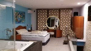 A modern hotel room with a large bed, a separate bathroom with a bathtub, and a large mirror. - Super Chic 3bd aptm. sauna/jacuzzi Mamitas Beach (Playa del Carmen)