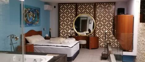 A modern hotel room with a large bed, a separate bathroom with a bathtub, and a large mirror.