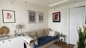 Une pièce moderne et bien éclairée, avec un canapé-lit, une petite table et une plante en pot.
