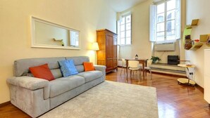 A living room with a grey sofa, a small table, and a TV. - "Ricasoli Premium" open space (Firenze)