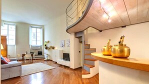 A modern living room with a curved staircase, a dining area, and a kitchen. - "Ricasoli Premium" open space (Firenze)