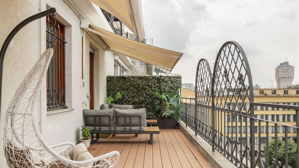 Un balcon avec un fauteuil suspendu, un canapé et des plantes en pot.