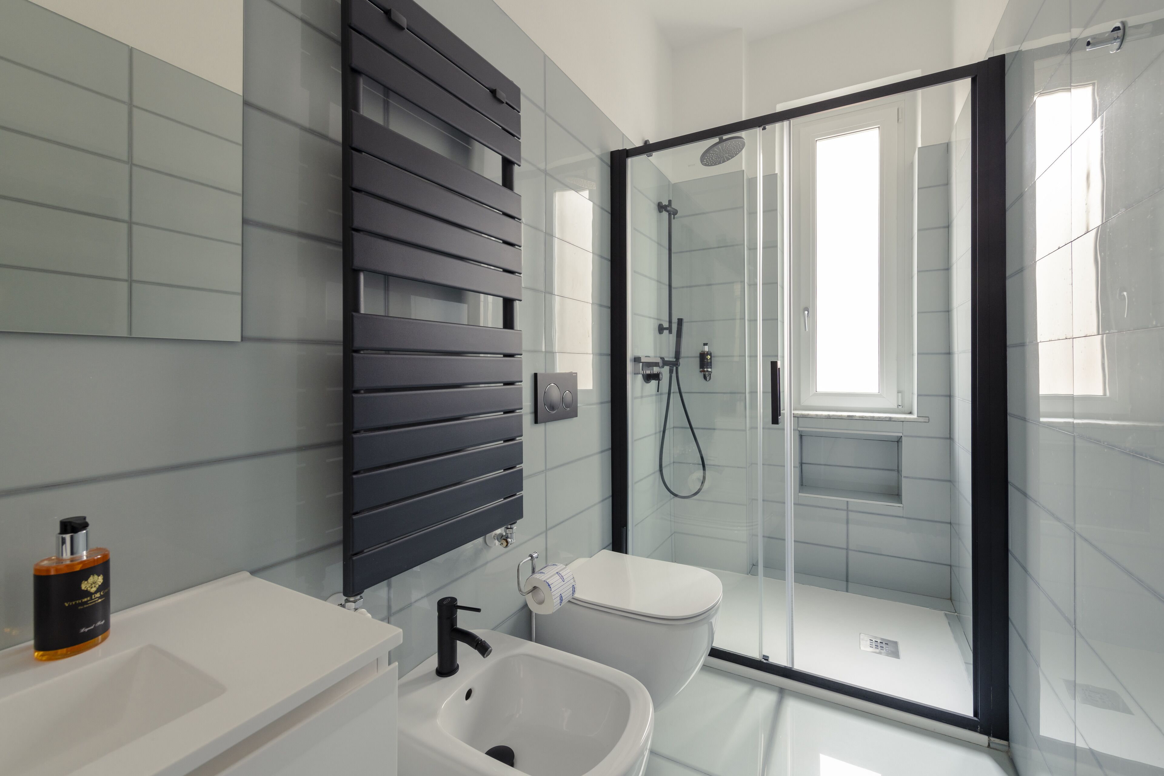 A modern bathroom with a glass-enclosed shower, a white sink, and a toilet.