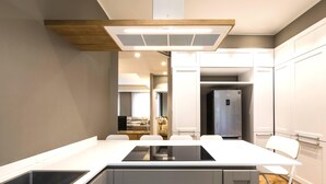 Une cuisine moderne dotée d’un îlot central, de meubles blancs et d’une cuisinière intégrée.