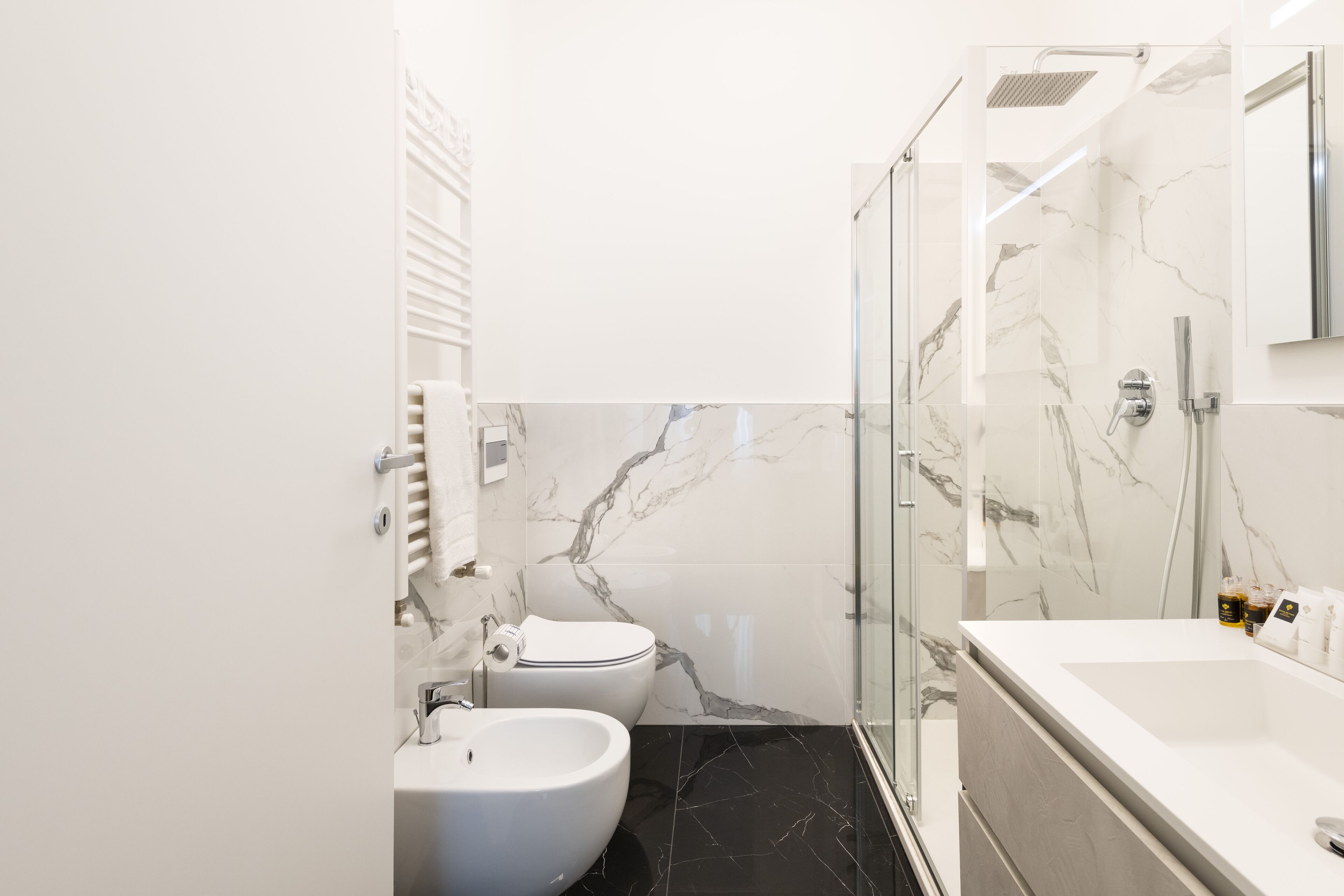 Un baño moderno con cabina de ducha de vidrio, un lavamanos blanco y una bañera.