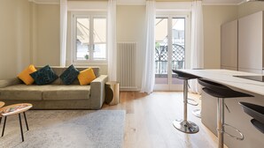 Un salon moderne avec un canapé, une table basse et un coin bar équipé de tabourets.