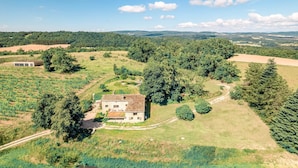 Une maison de campagne entourée de champs et d’arbres.