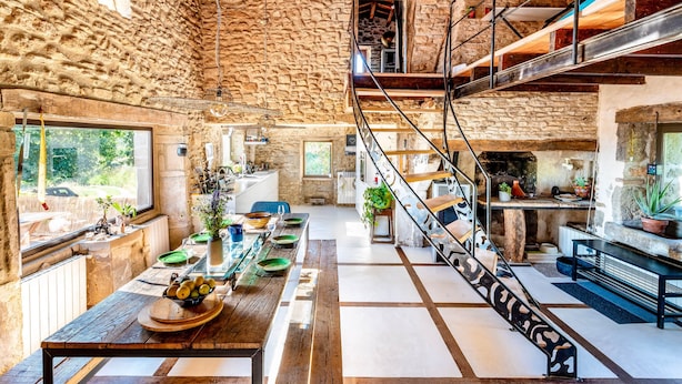 Un intérieur rustique en pierre comprenant un coin repas, une cuisine et un escalier.