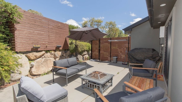 An outdoor patio area with a barbecue grill, a fire pit, and a seating arrangement including a sofa and chairs. - Jackson Hole 3 - 3/123 Gippsland Street (Jindabyne)