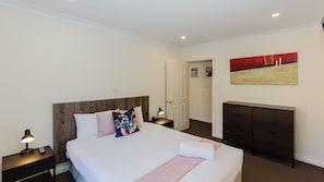 Una camera d'albergo con un letto, comodini, una cassettiera e un quadro appeso al muro.