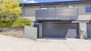 A two-story house with a garage, a covered porch, and a stone retaining wall. - Jackson Hole 3 - 3/123 Gippsland Street (Jindabyne)