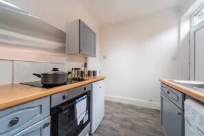 A compact kitchen with a stove, oven, and dishwasher, wooden countertops, and light-colored walls. - The Miracle Spacious 2 Bedroom 3 Beds Central Hull (Kingston upon Hull)