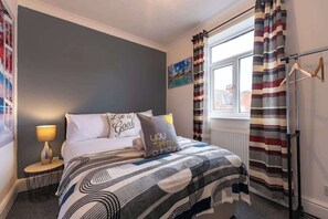 A bedroom with a bed, two bedside tables, a window with curtains, and a wall with a painting. - The Miracle Spacious 2 Bedroom 3 Beds Central Hull (Kingston upon Hull)