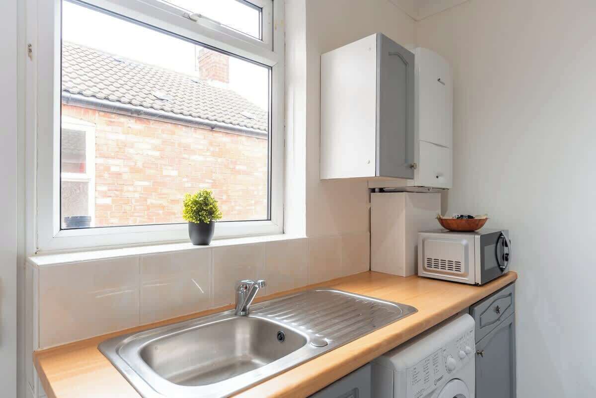 A kitchen with a sink, a microwave, and a dish drying rack.