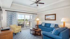 A room with a blue sofa, a yellow armchair, a wooden coffee table, and a ceiling fan. - Worldmark Reunion (Kissimmee)