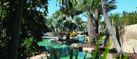 A serene pool area surrounded by lush greenery and palm trees.