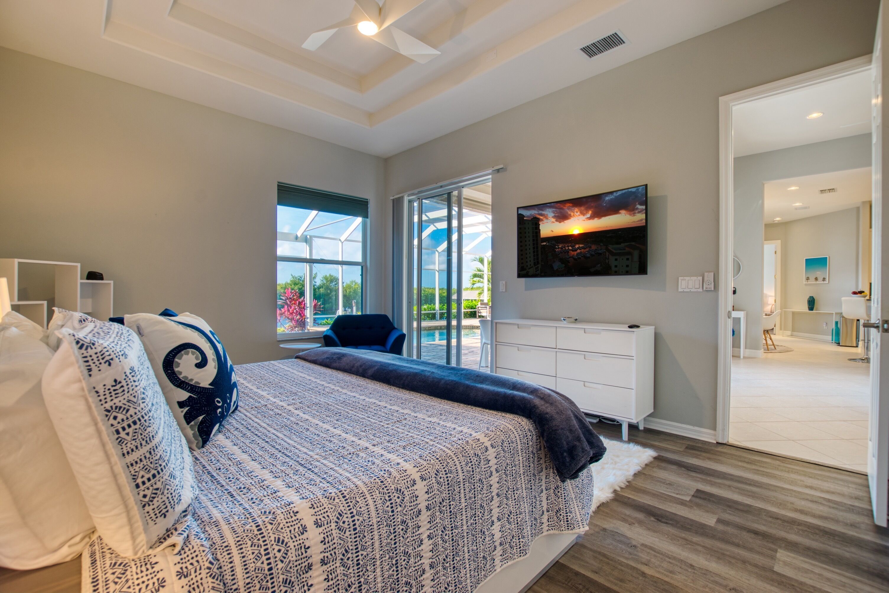 Un dormitorio moderno con una cama grande, un televisor y un ventanal corredero a un balcón.