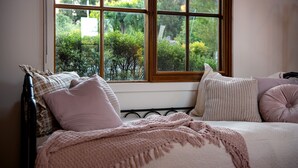 Un dormitorio con cama, almohadas y vistas a la vegetación por una ventana.