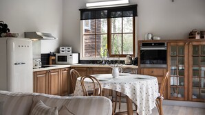 Cocina compacta con armarios de madera, un refrigerador blanco, un microondas y un comedor con una mesa lista para dos comensales.