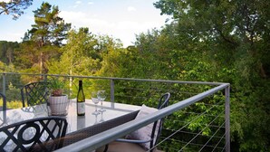 Un área de comedor al aire libre con una mesa lista para dos personas, una botella de vino y dos copas.