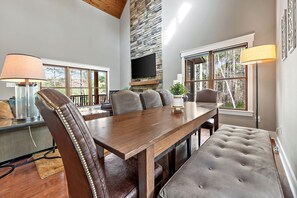 A modern dining area with a wooden table, leather chairs, and a stone accent wall.