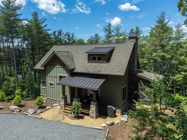 A two-story house with a stone chimney, a covered porch, and a small window. - Wildside Retreat | Lake James | Pool & Resort Community Access | 3 BR | Pet-Friendly (Nebo)