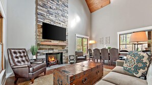 A cozy living room with a stone fireplace, leather armchair, and a unique wooden coffee table.