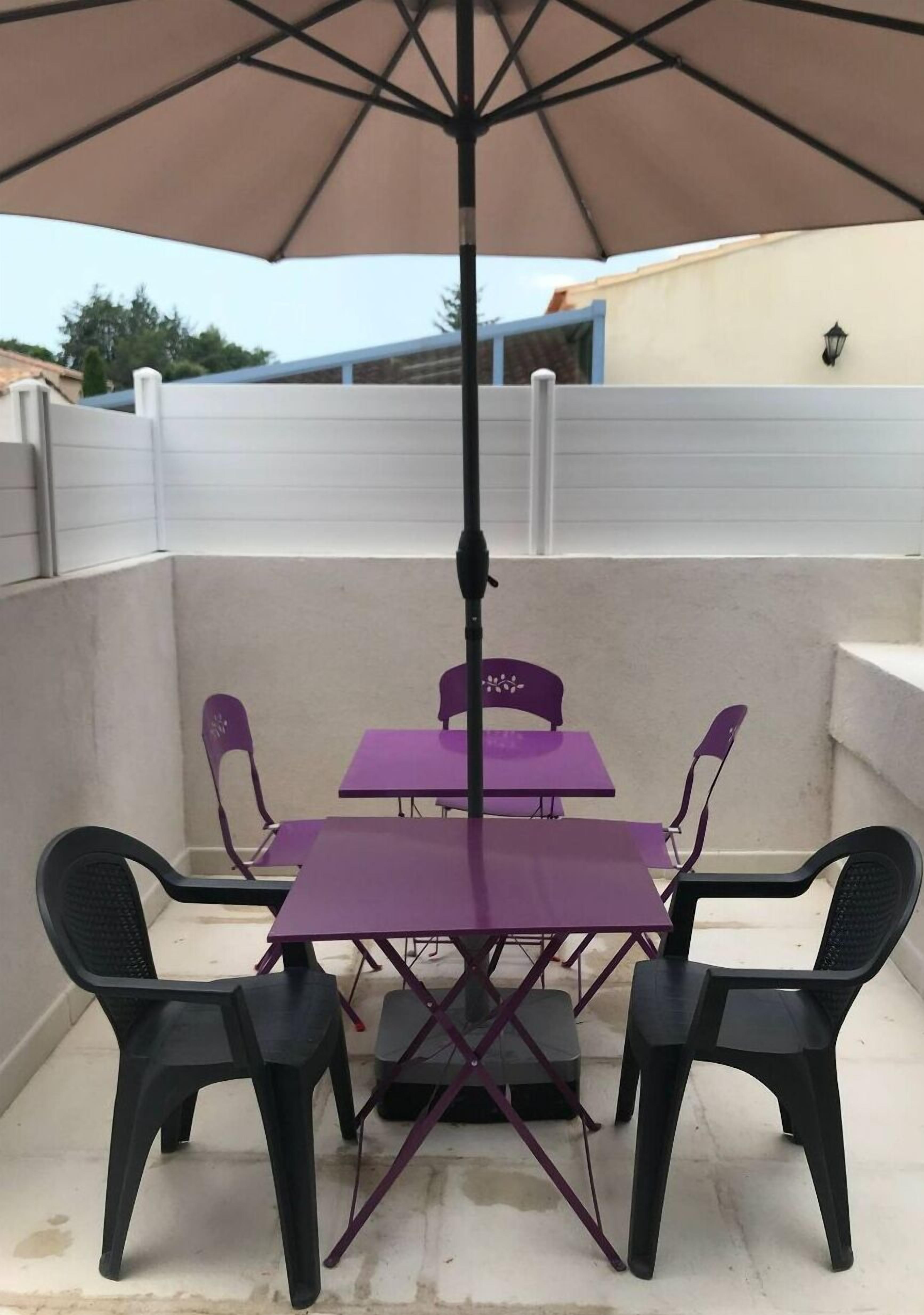 An outdoor patio with a table and chairs under a large umbrella.