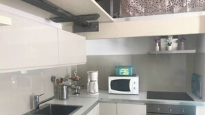 Ett modernt kök med vita skåp, en diskho i rostfritt stål, en kaffebryggare, en mikrovågsugn och en ugn.
