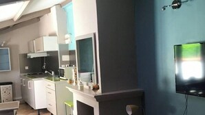 A modern kitchen with white cabinets, a built-in oven, and a TV mounted on the wall. - House (Mimet)