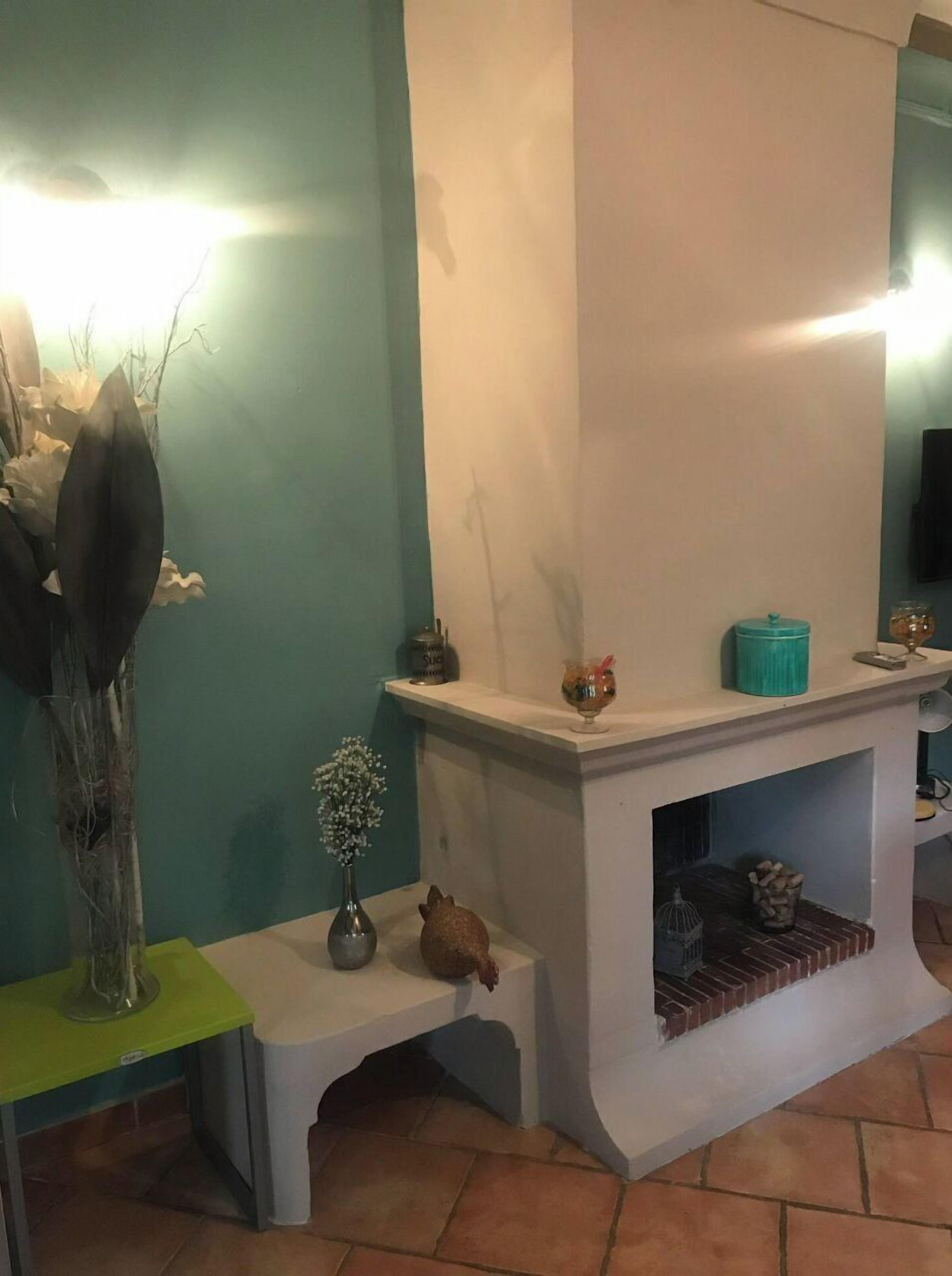 A room with teal walls, a white fireplace, and a small table with decorative items.