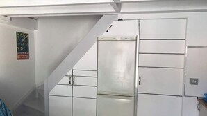 Une chambre compacte avec un placard intégré, un lit avec une literie à rayures et une affiche accrochée au mur.