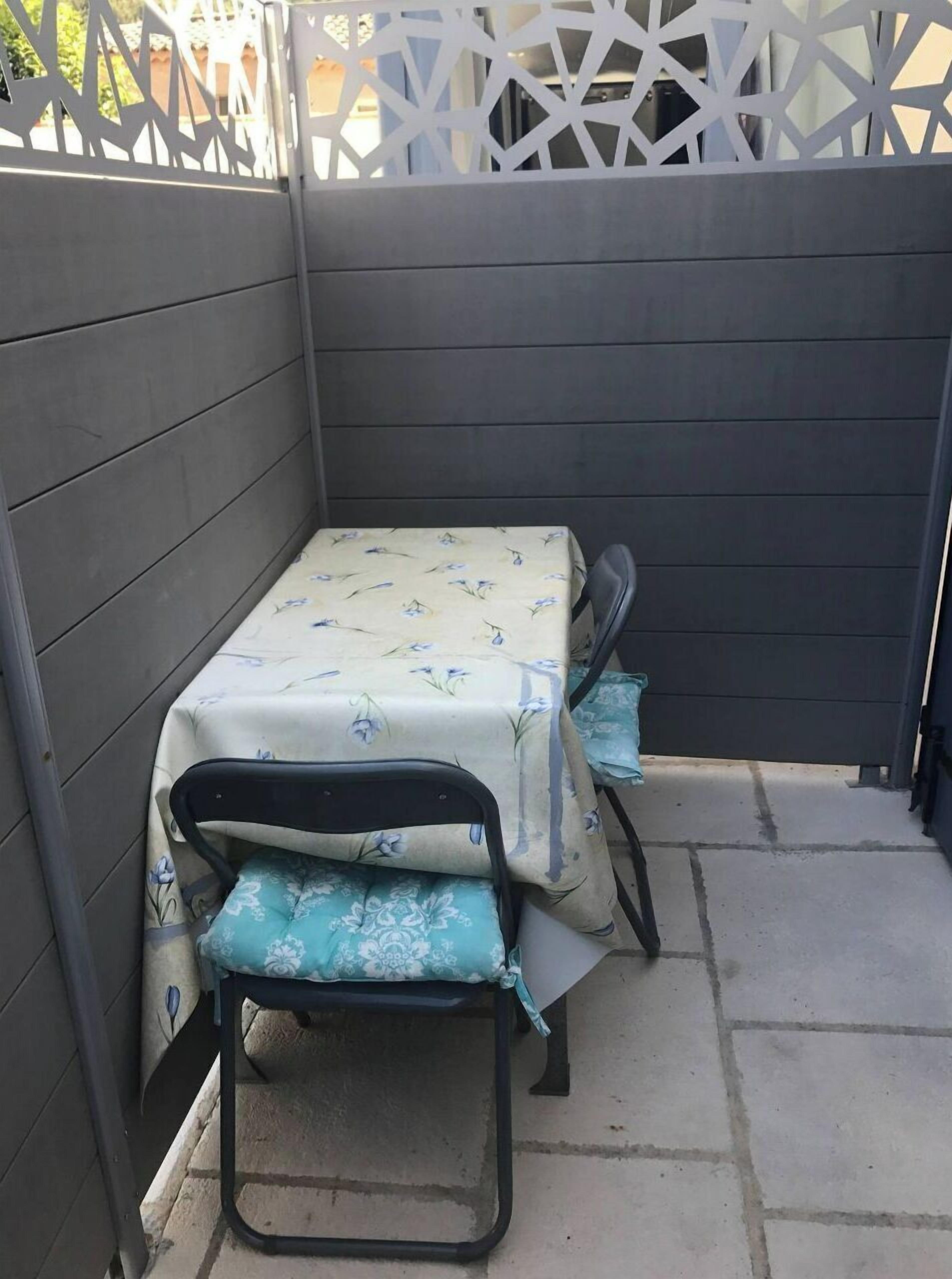 Une petite terrasse extérieure avec une table et deux chaises.