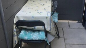 Une petite terrasse extérieure avec une table et deux chaises.