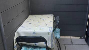 Une petite terrasse extérieure avec une table et deux chaises.