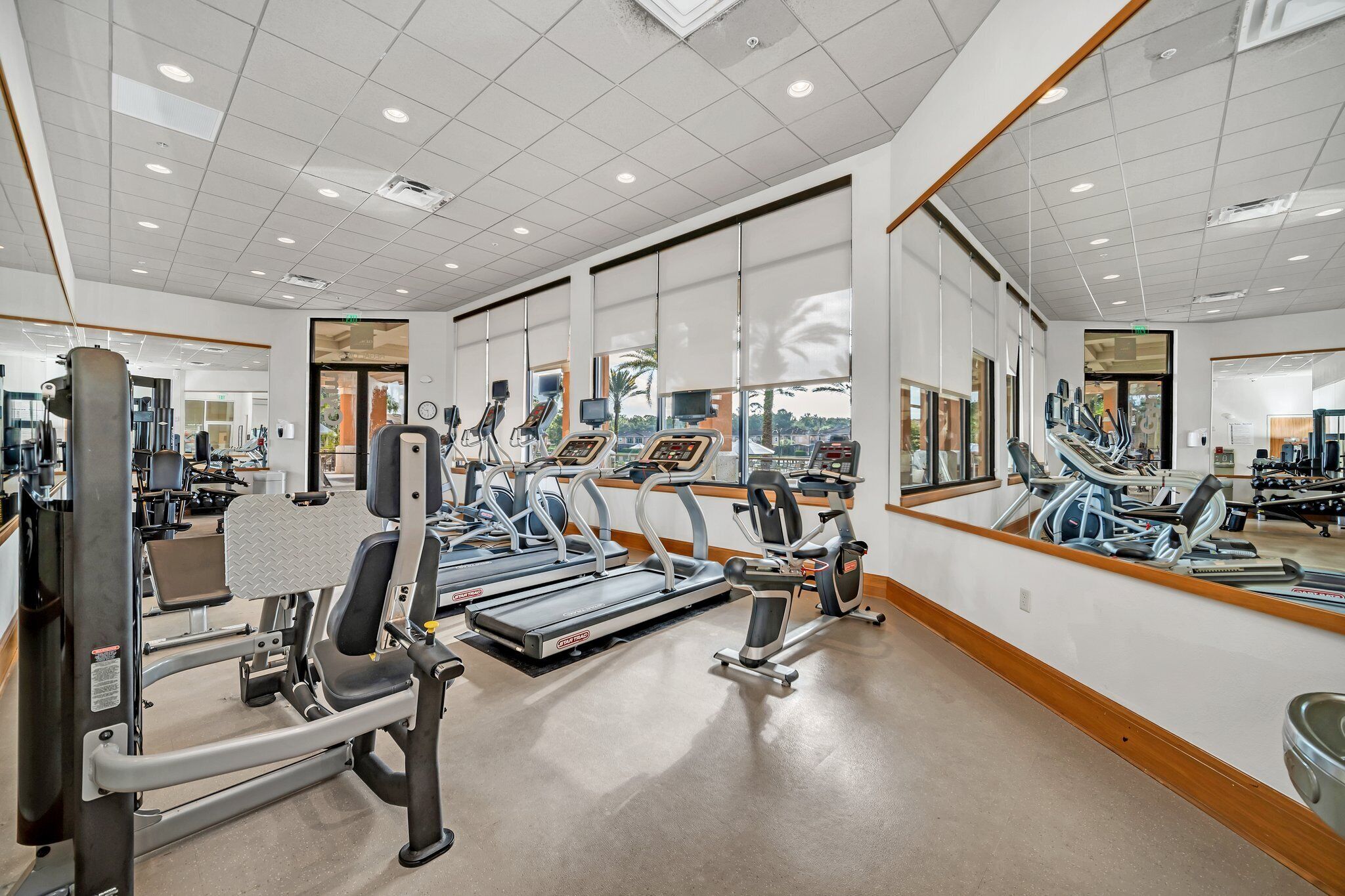 Une salle de sport équipée de tapis de course, d’appareils de musculation et de miroirs.