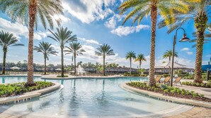 A swimming pool surrounded by palm trees and a brick walkway.
