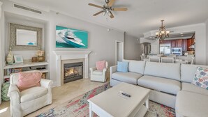A living room with a fireplace, a ceiling fan, and a large painting of a boat.