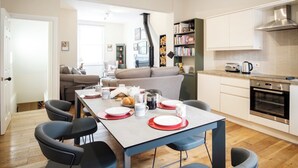 A modern kitchen with a dining area, featuring a central island, built-in oven, and a bookshelf. - Sleeps 18 Central York 5★Townhouse Parking Cinema & Pool Table & Games Room (York)
