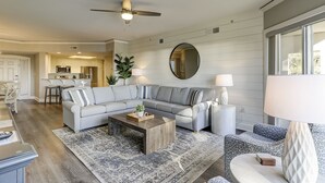A modern living room with a sectional sofa, a coffee table, and a round mirror. - 3106 Windsor Court S - Amazing Oceanfront Villa in Palmetto Dunes! (Hilton Head Island)