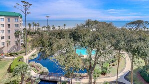 A resort with a pool surrounded by trees, a beach view, and a building with balconies. - 3106 Windsor Court S - Amazing Oceanfront Villa in Palmetto Dunes! (Hilton Head Island)