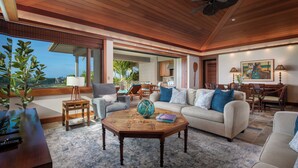 A spacious living room with a large window, a wooden ceiling, and a cozy seating area. - Hualalai Waiulu Villa 133B ~ Updated, Spacious with Great Views! (Kailua-Kona)
