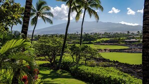A lush golf course with palm trees, a clear sky, and a mountain in the background. - Hualalai Waiulu Villa 133B ~ Updated, Spacious with Great Views! (Kailua-Kona)